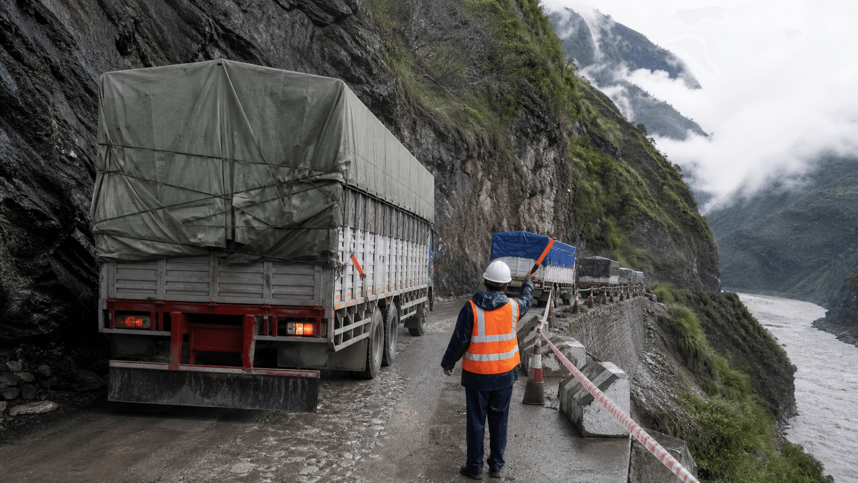 Container trucks moving slowly on a restricted temporary mountain road toward Tatopani customs